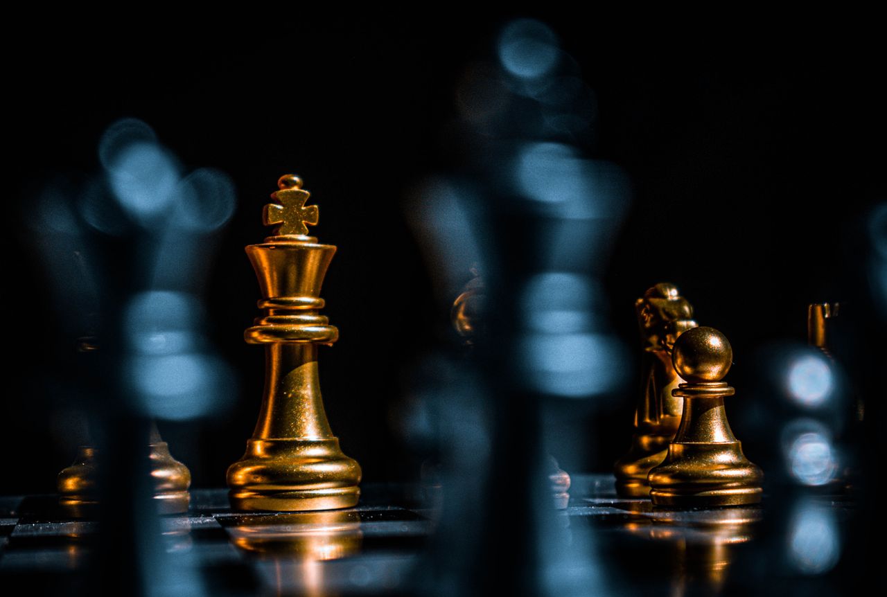 services-img-02 Captivating close-up of gold chess pieces on a board with a dramatic black background.
