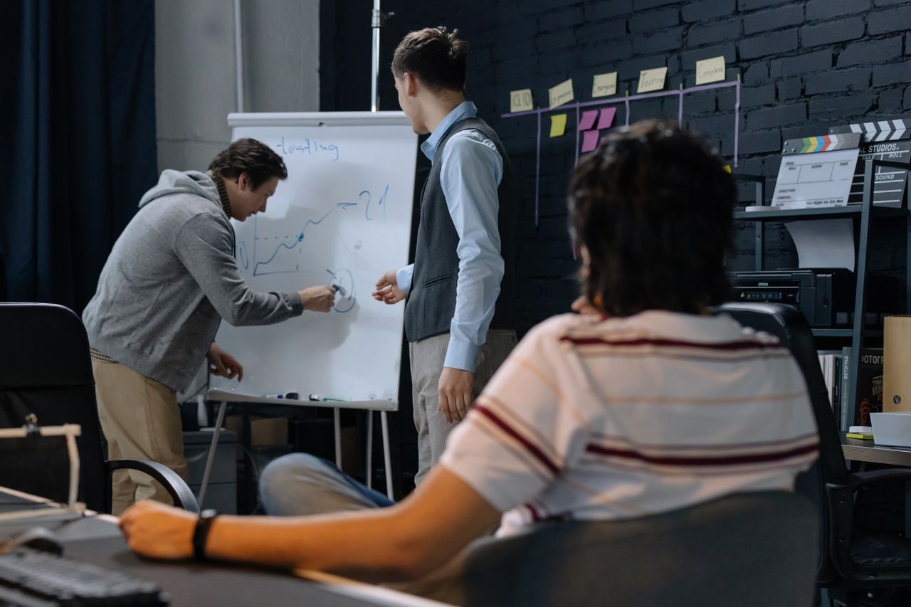 Services Team members brainstorming at work discussing a business strategy on a whiteboard.
